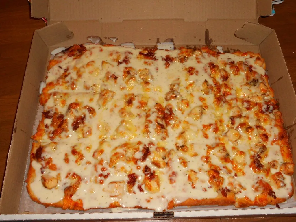 Homemade chicken bacon ranch pizza with melted cheese, crispy bacon, and creamy ranch sauce on a golden crust.