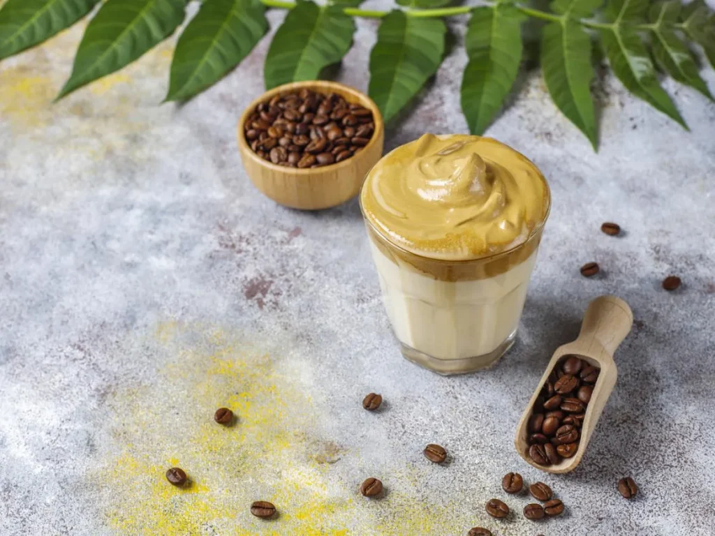 Fluffy whipped Dalgona coffee served over iced milk in a clear glass, topped with creamy coffee foam