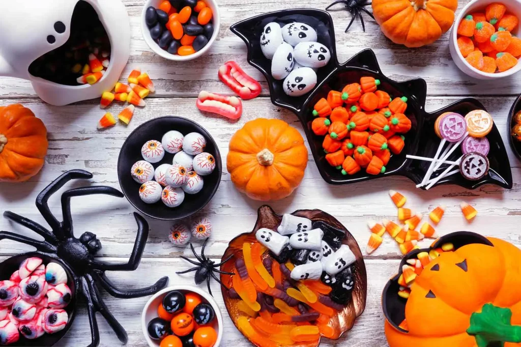 Homemade Halloween desserts and candies displayed with pumpkins, spiderwebs, and fall decorations.