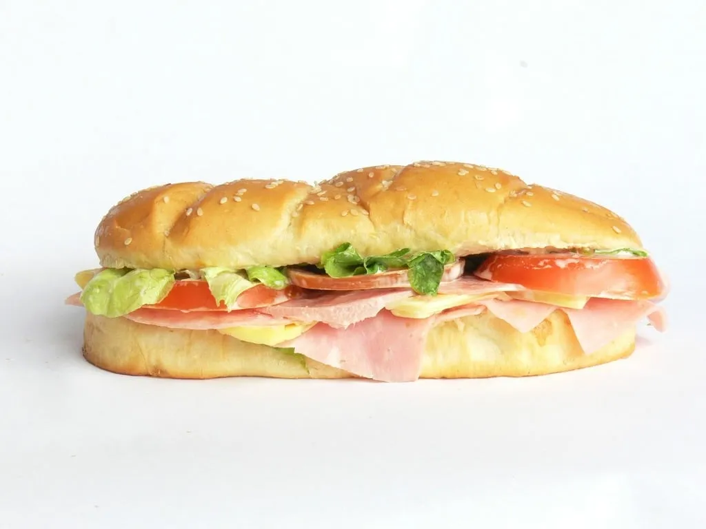 Classic Italian hoagie sandwich with layers of meats, cheese, lettuce, tomato, and banana peppers on a hoagie roll.
