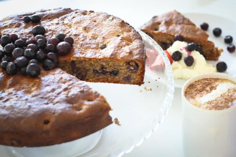 Slice of homemade blueberry cake served with fresh berries and powdered sugar