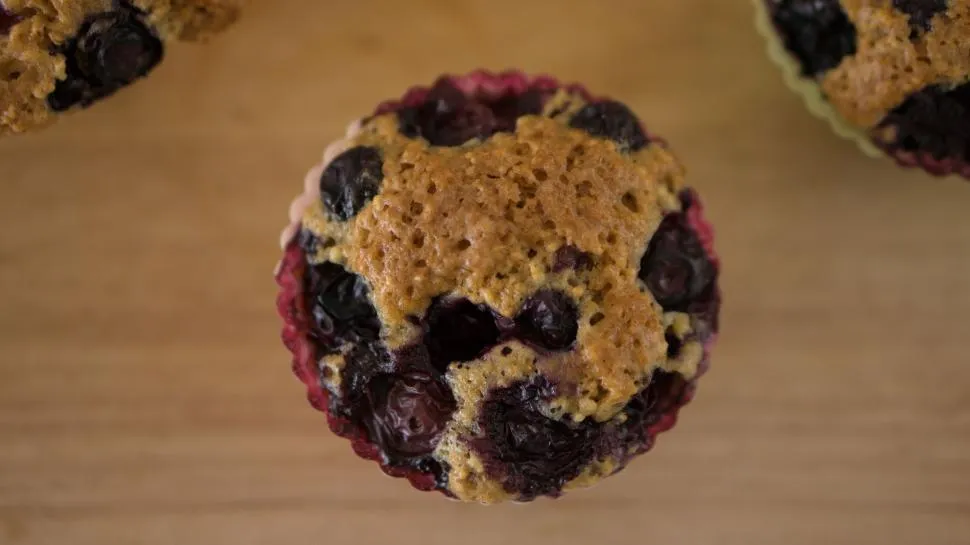 Close-up of freshly baked blueberry muffins with golden tops and juicy blueberries inside.