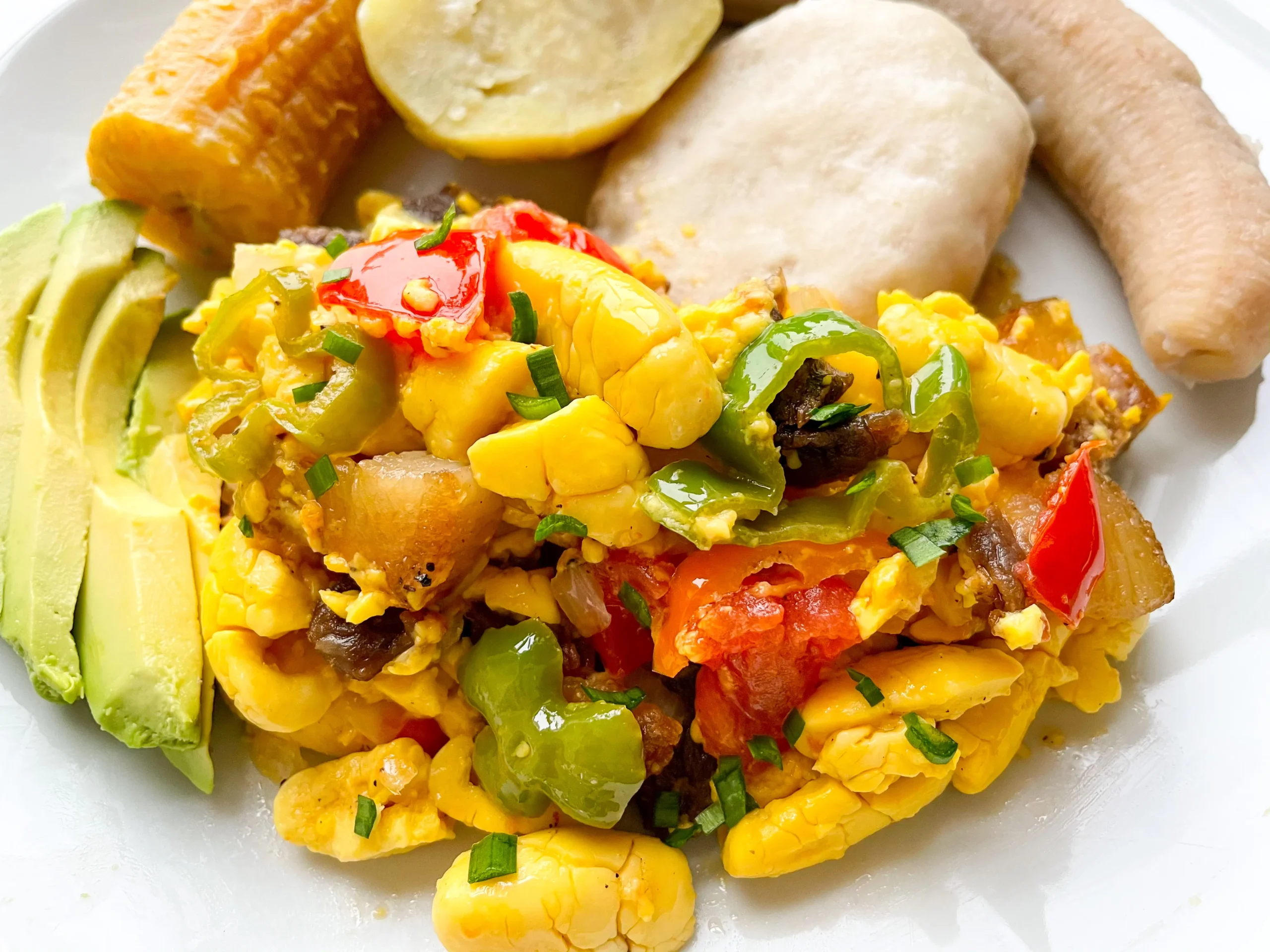 Authentic Jamaican ackee and saltfish breakfast served with fried dumplings and plantains on a traditional plate