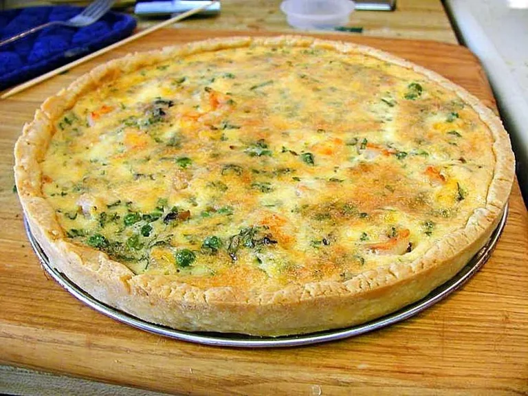 Fluffy homemade breakfast quiche with golden crust and melted cheese served on a white plate