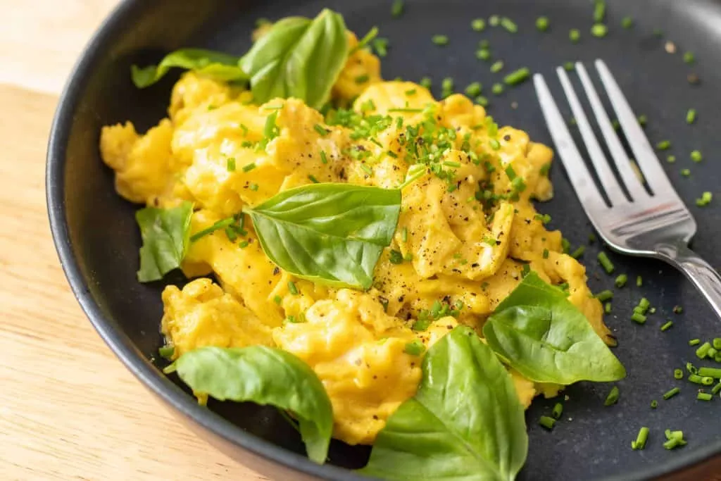 Soft and creamy scrambled eggs with melted cheese in a skillet