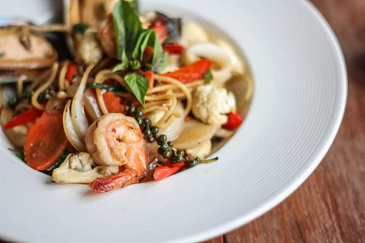 Creamy shrimp macaroni salad with fresh vegetables served in a white bowl