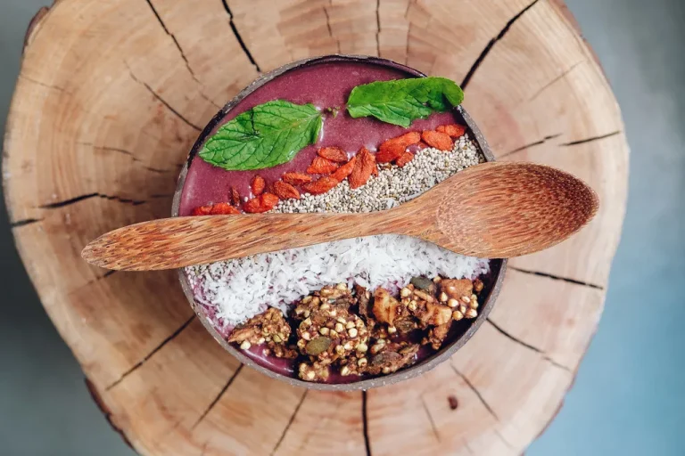 Healthy homemade açaí bowl with colorful fruit toppings and coconut flakes in a wide breakfast bowl