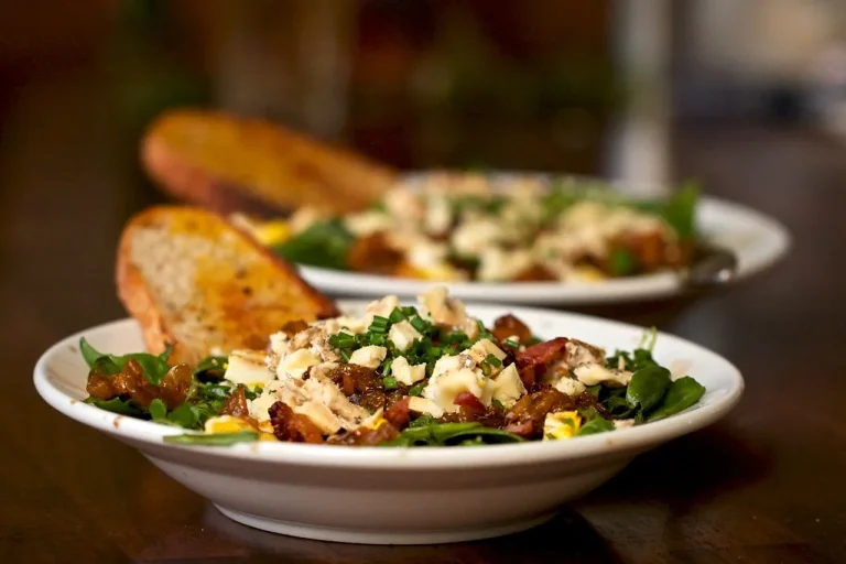 Fall salad bowl featuring seasonal greens, cranberries, squash, and maple Dijon dressing.