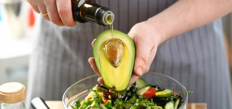 Close-up of creamy avocado salad with herbs and olive oil on a white plate