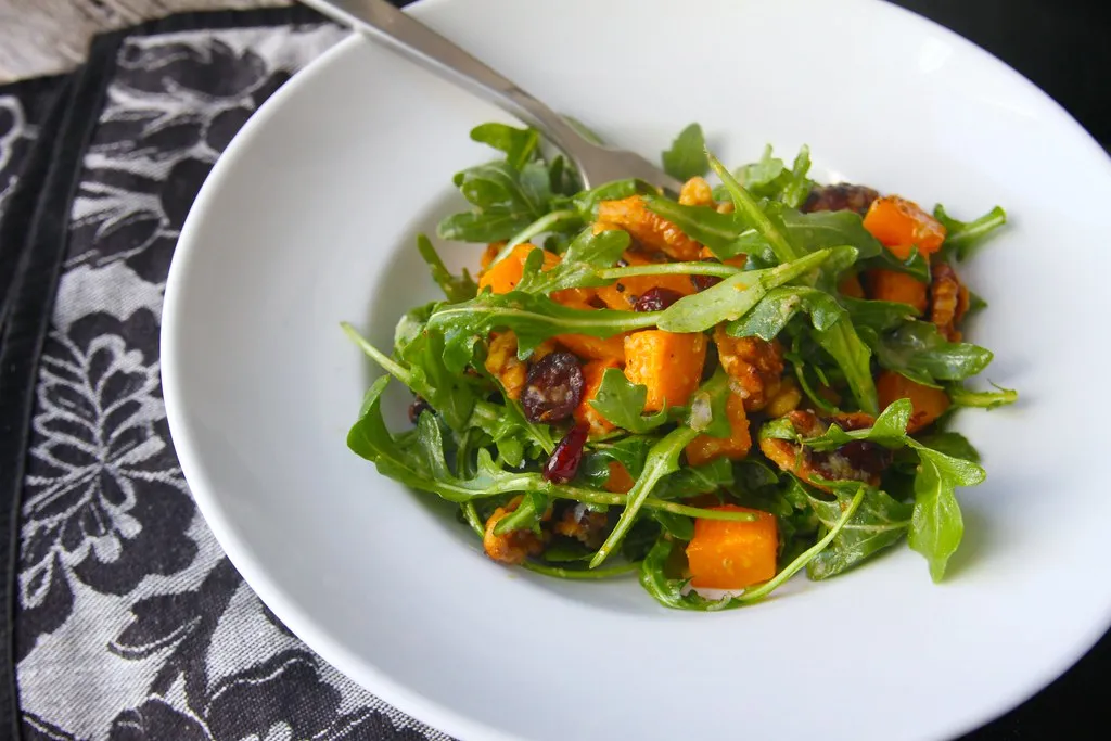 Vegan butternut squash salad with roasted squash, kale, quinoa, nuts, and maple dressing