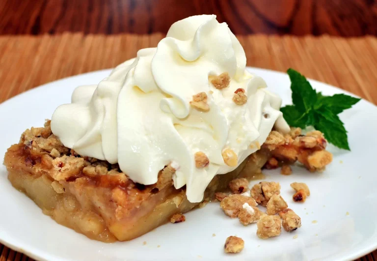 Serving of apple crisp with vanilla ice cream on a rustic plate.