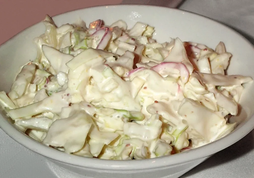 Close-up of creamy homemade coleslaw with shredded cabbage and carrots in a white bowl