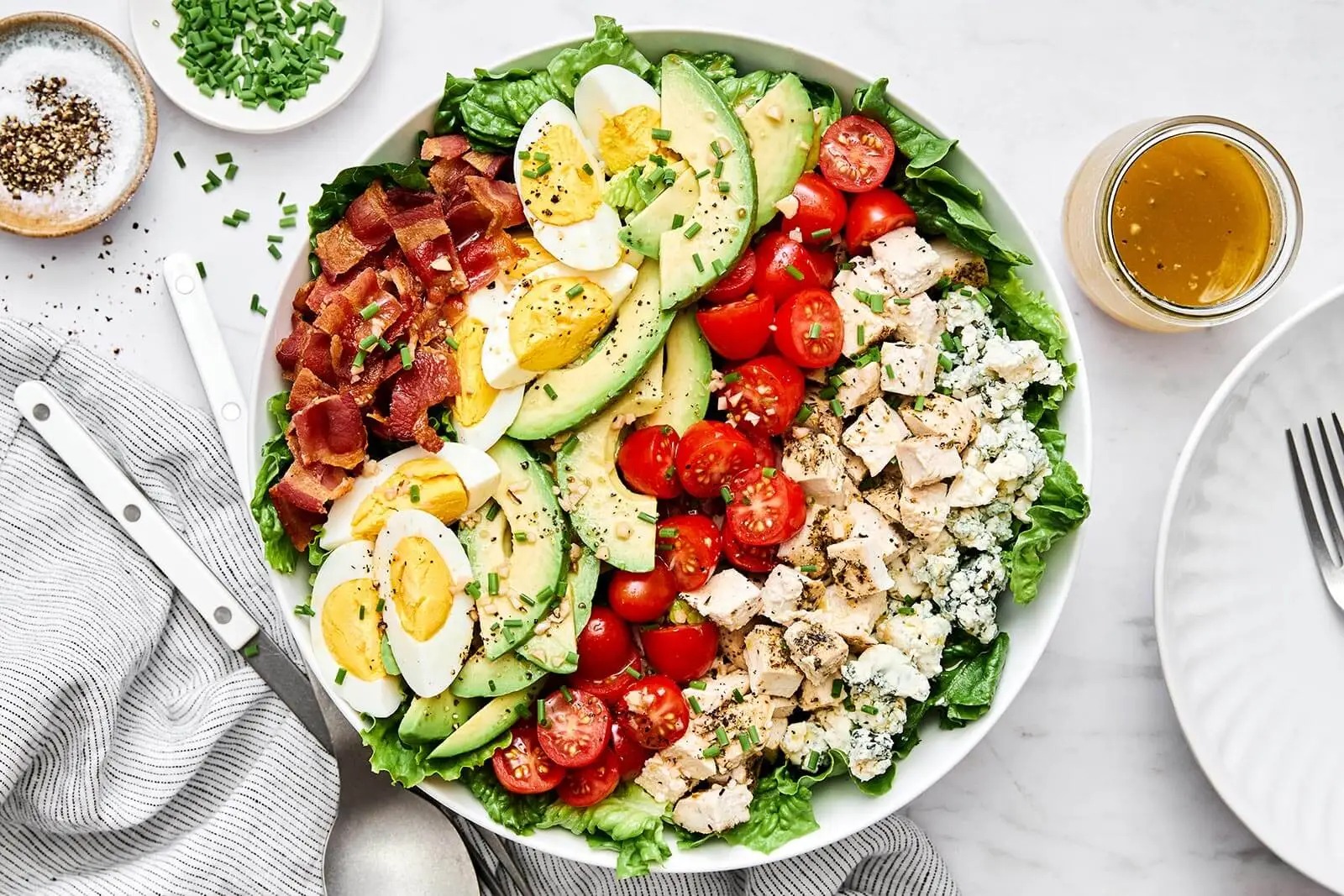 Classic Cobb salad with layers of chicken, bacon, avocado, eggs, and blue cheese on a plate