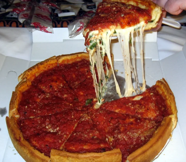 Slice of Chicago deep-dish pizza showing thick crust and layers of cheese and sausage