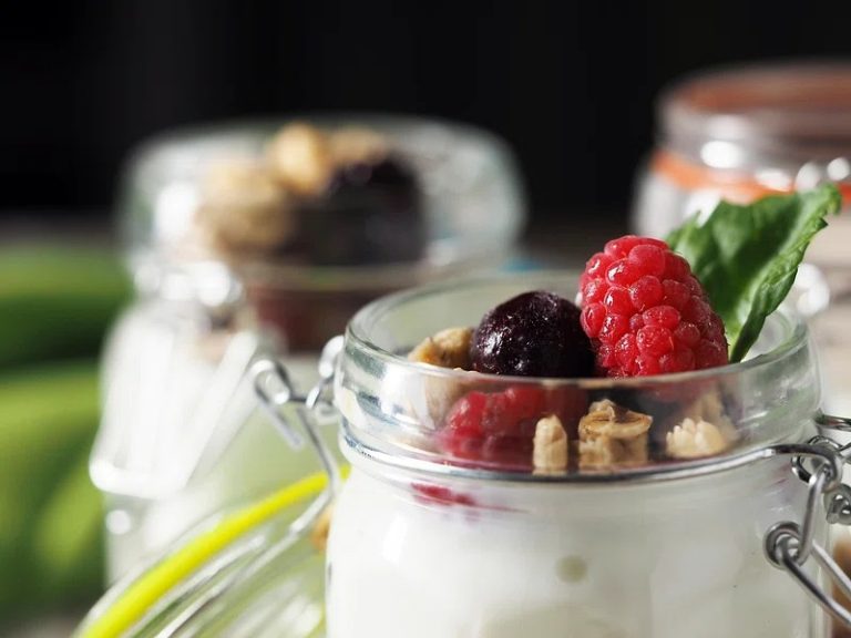 Healthy overnight oats meal prep jars with yogurt, chia seeds, and fruit on a wooden table.