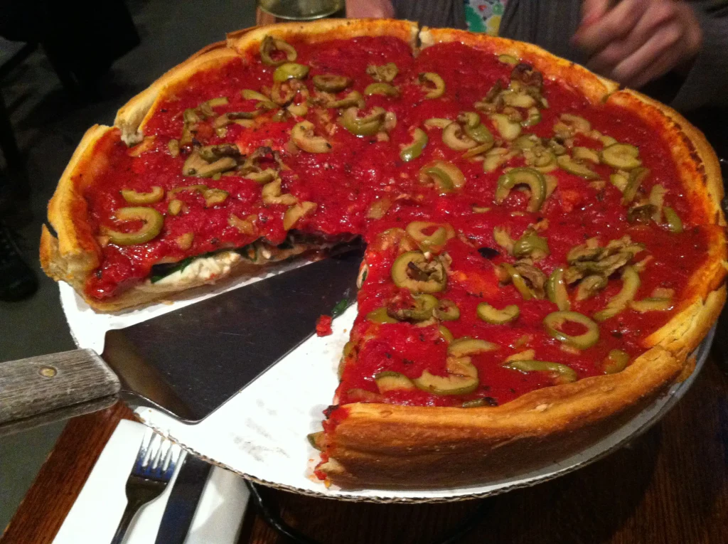 A golden, cheesy Chicago-style deep-dish pizza with tomato sauce and fresh toppings