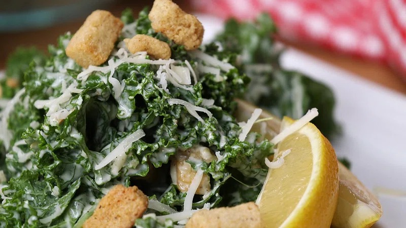 Fresh kale Caesar salad with creamy dressing, Parmesan, and crunchy croutons in a bowl.