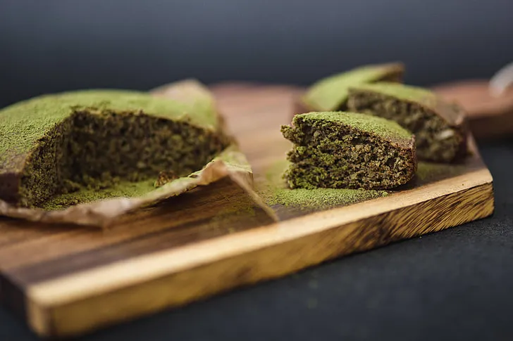 Slice of Japanese matcha cake garnished with powdered matcha