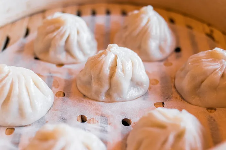 Close-up of homemade dumplings being folded and prepared for steaming.