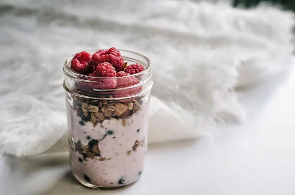 A mason jar filled with creamy overnight oats topped with fresh blueberries and sliced bananas.