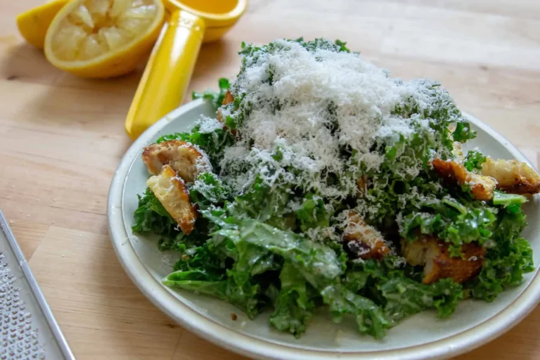 Close-up of massaged kale leaves tossed with homemade Caesar dressing and grated Parmesan.